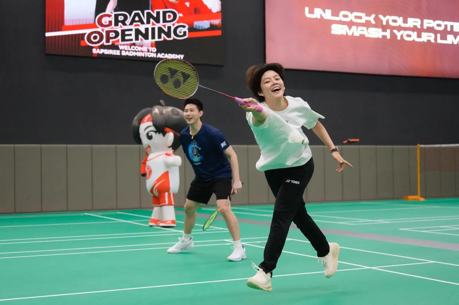 Sapsiree Taerattanachai playing badminton with guests at the academy